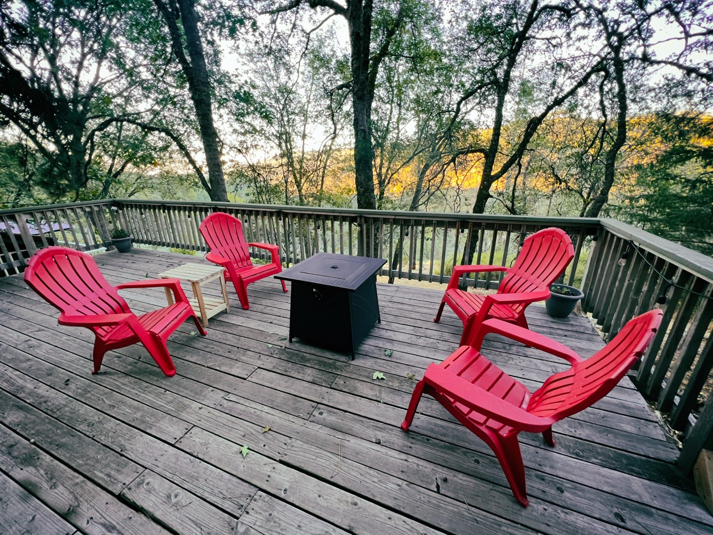 Wraparound deck with red Adirondack chairs overlooking the tree canopy at golden hour
