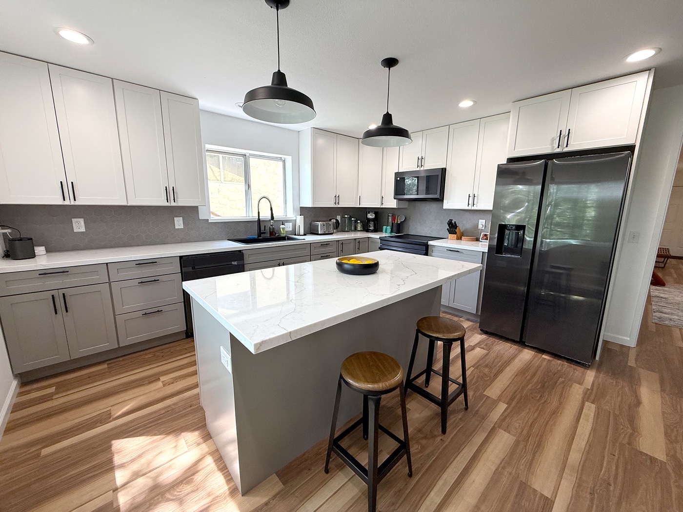 Wide view of the designer kitchen with quartz island, pendant lights, and hardwood floors